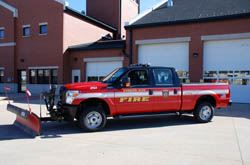 A black and red truck with a plow shovel connected to the front.